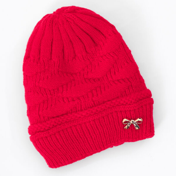 A red knit beanie with a diamond pattern and a ribbed cuff. A small, gold-colored bow-shaped embellishment is attached to the front of the cuff.